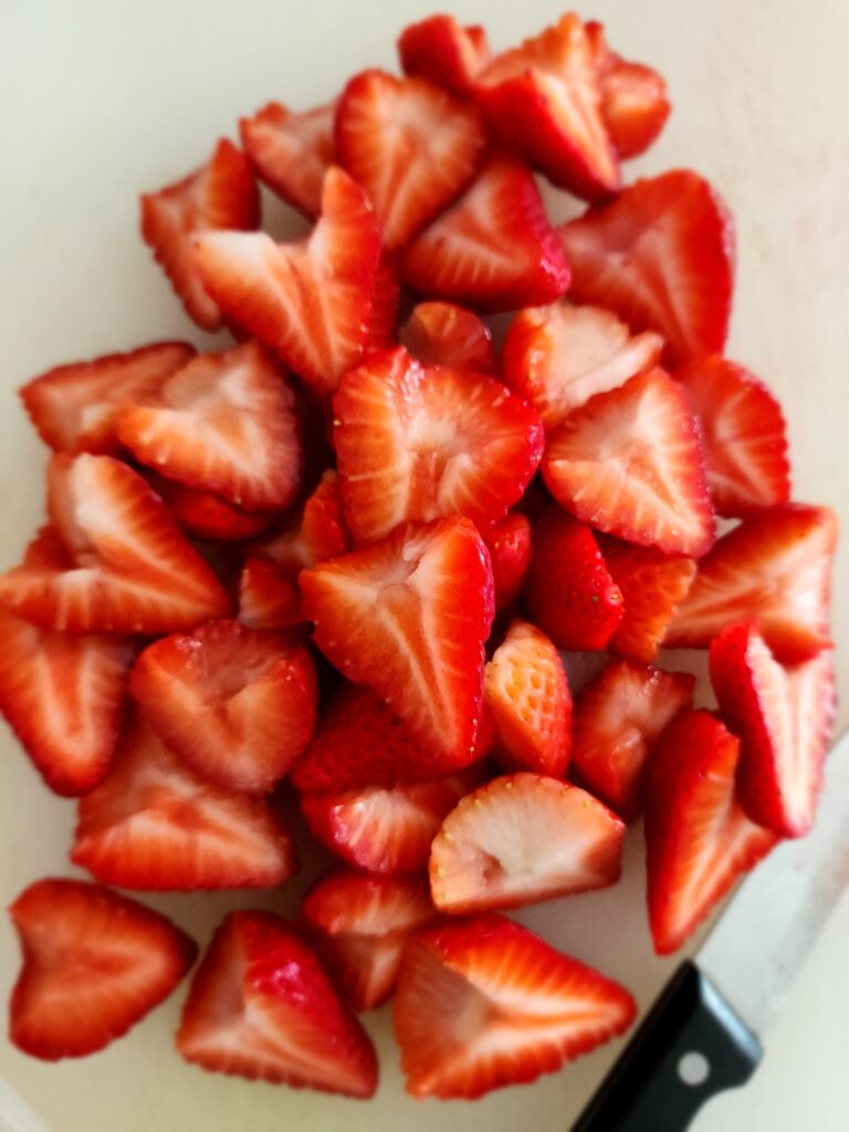 Cut up strawberries for a topping on the olive oil cake