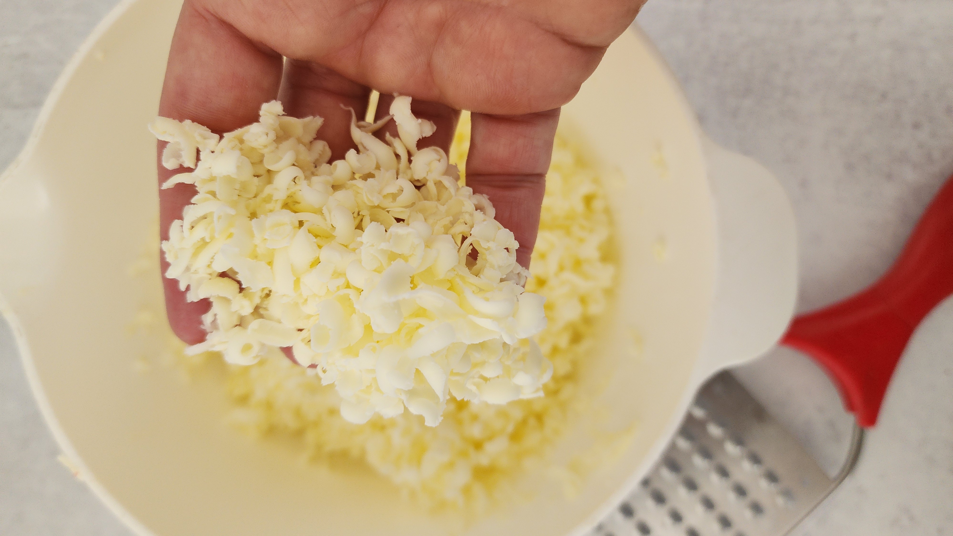 Hand holding butter that has been grated