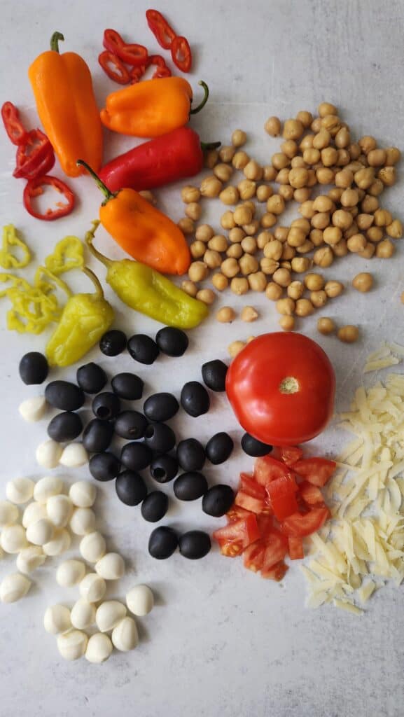 'Italian' Pasta Salad ingredients:  peppers, pepperoncini, black olives, tomatoes, parmesan and Mozzarella cheese, and chickpeas