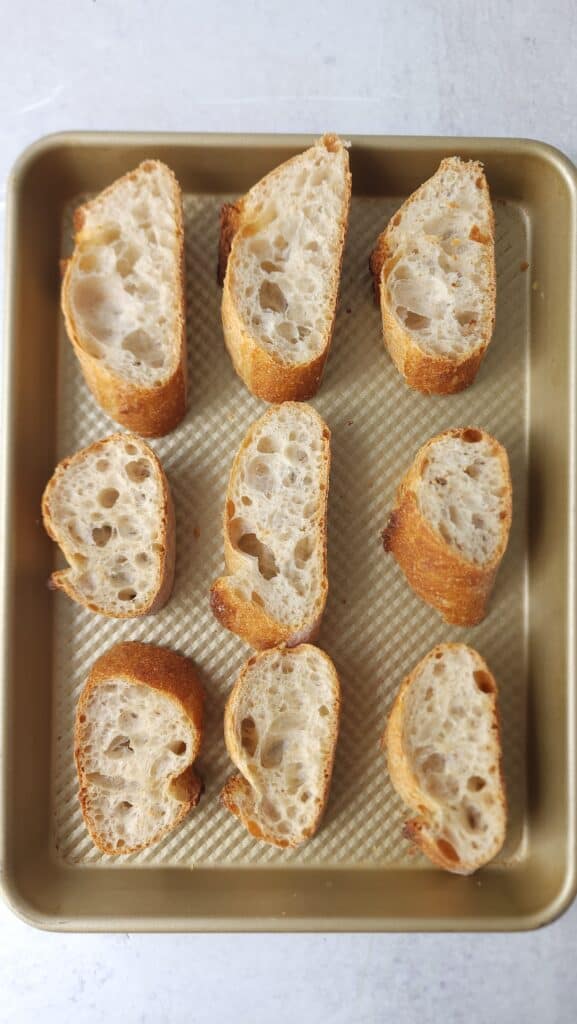 Bread slices pre-toasting on a baking sheet