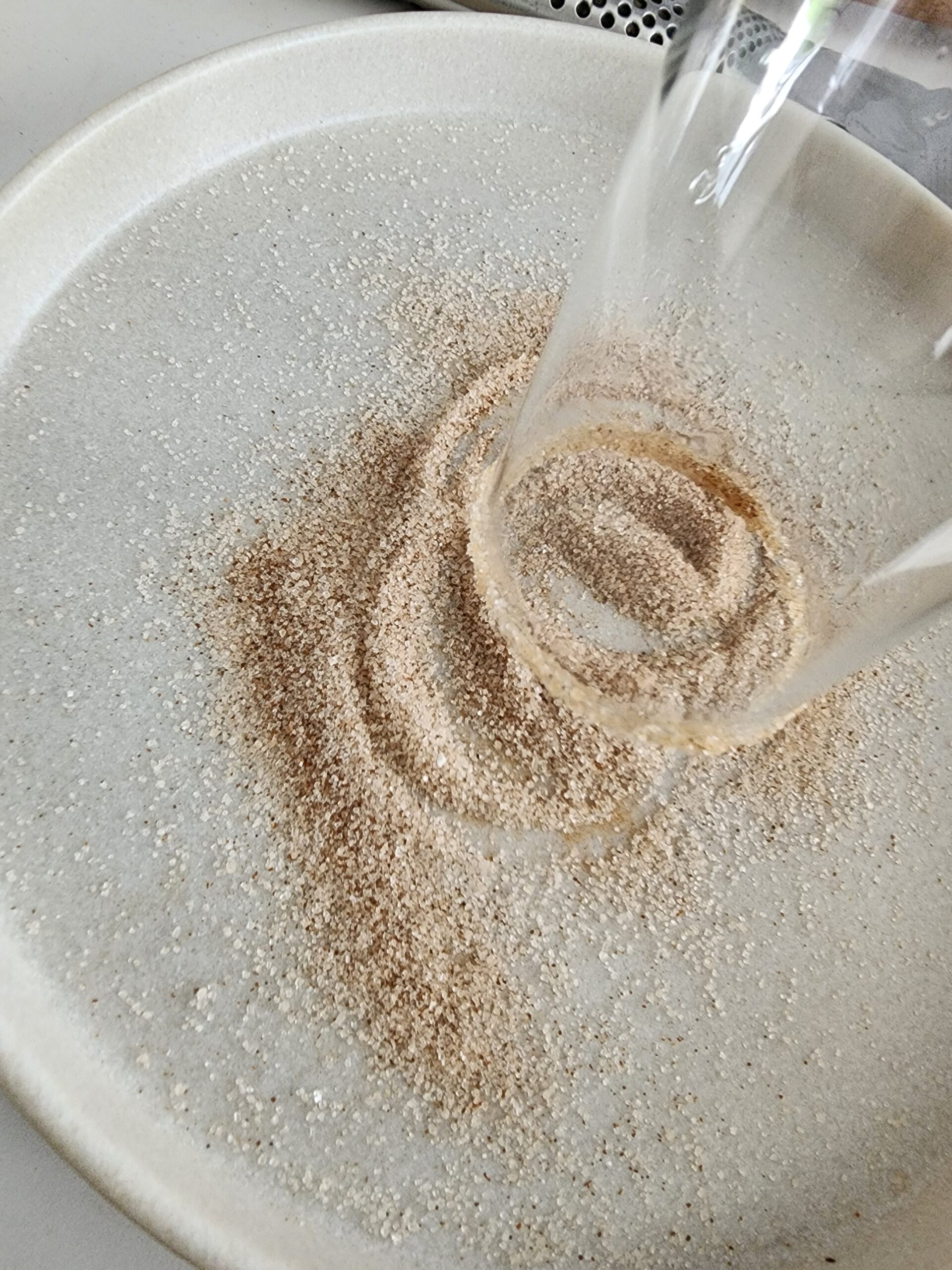 Placing the outer edge of a glass in cinnamon sugar