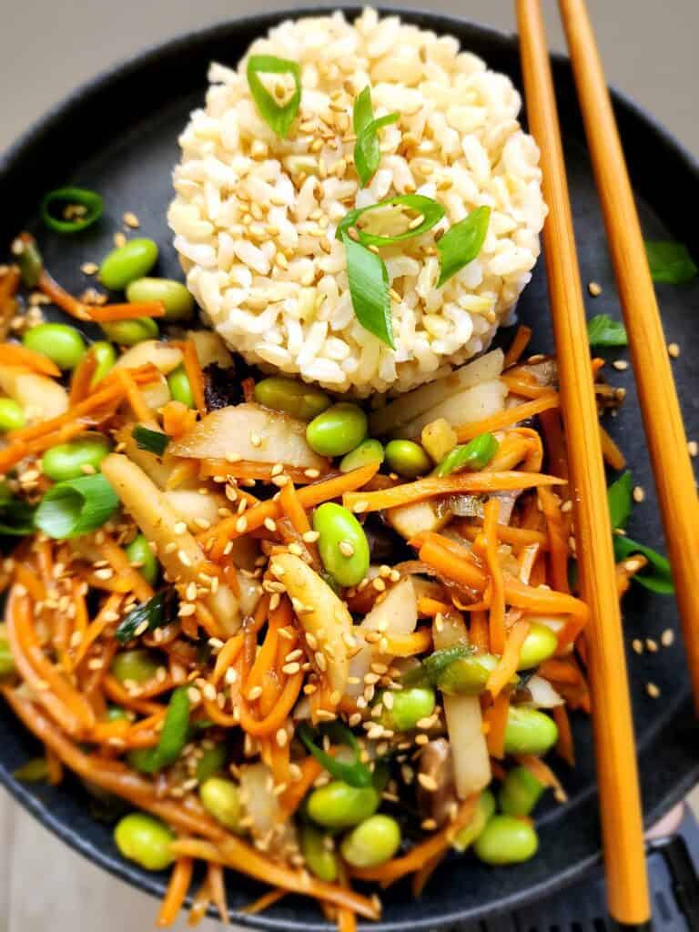 Close-up plated easy veggie stir-fry with brown rice and chopsticks