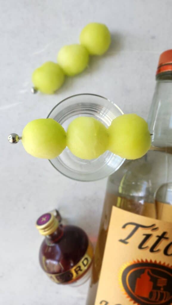 3 honeydew balls on top of a glass on a skewer stick