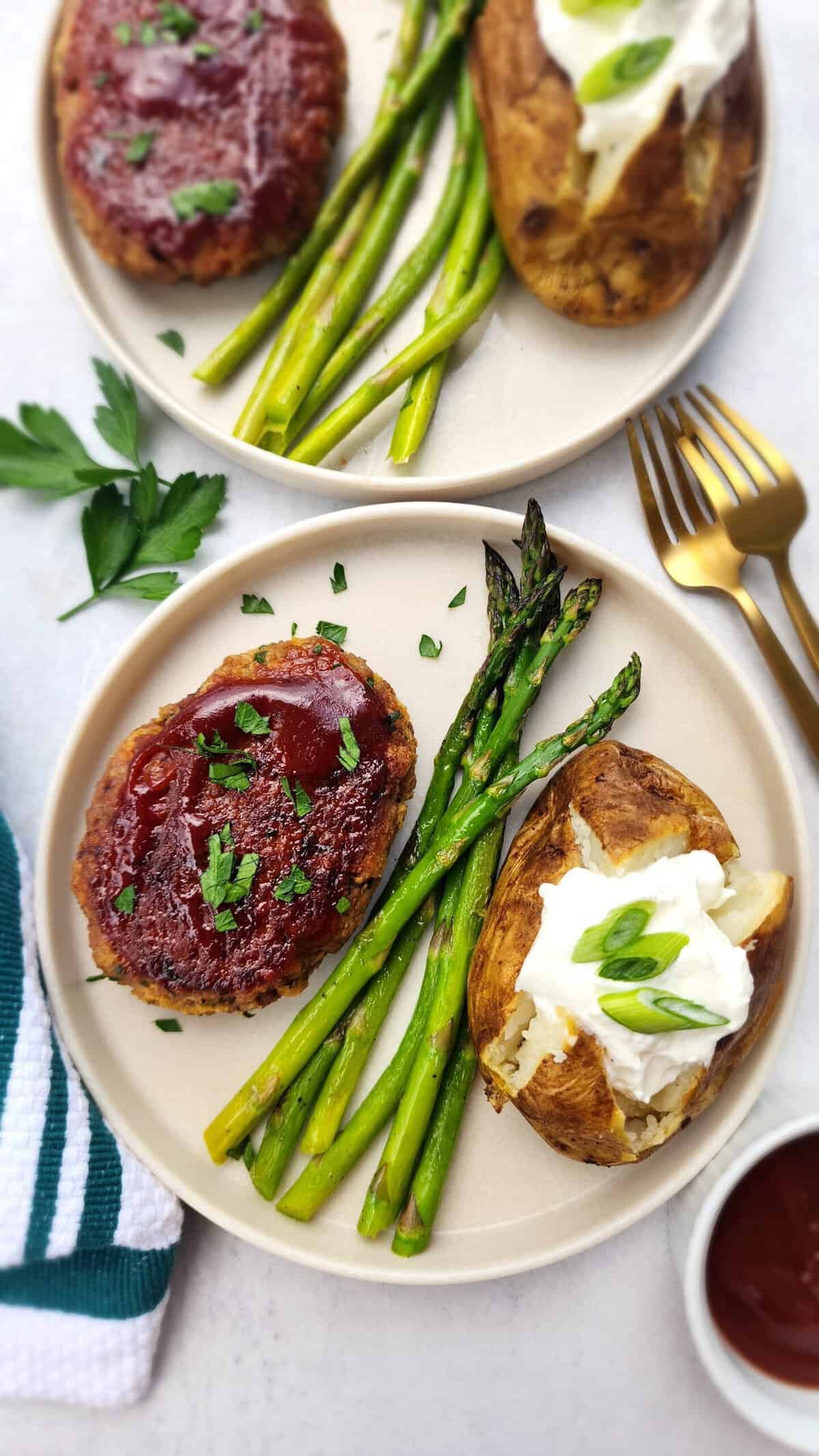 plate of glazed meatloaf with roasted asparagus and baked potato