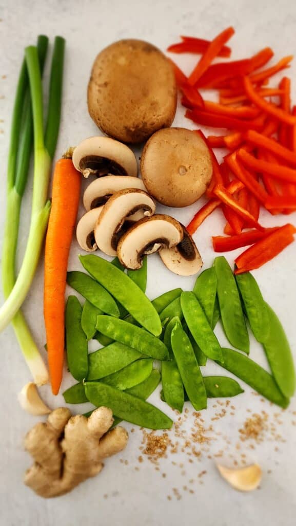 ingredients for an easy veggie stir-fry: scallions, ,carrot, mushrooms, snow peas, red pepper, ginger, garlic