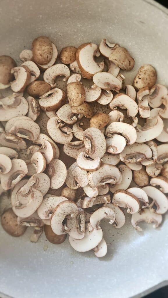 raw mushrooms being sauteed in a frying pan